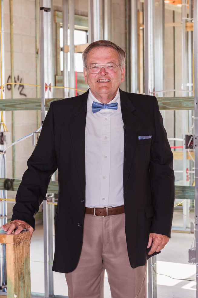 a person in a suit and bow tie standing in front of a construction site